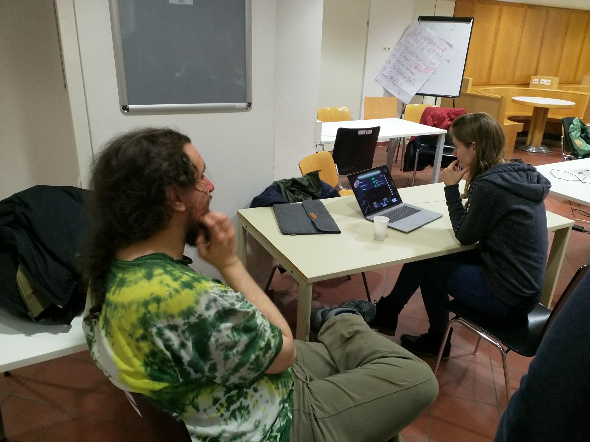 Visitor playing "Sacrifices are made in China" while one of the creators is watching